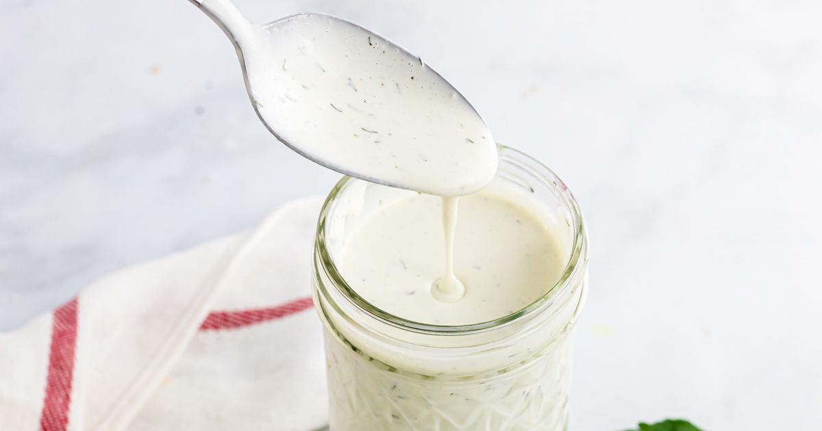 spoon pouring keto ranch dressing into a jar