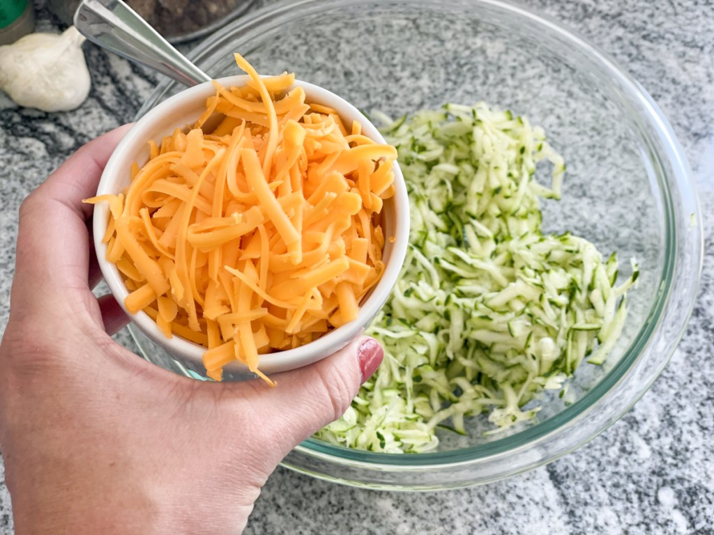 shredded zucchini in a bowl with shredded cheddar cheese