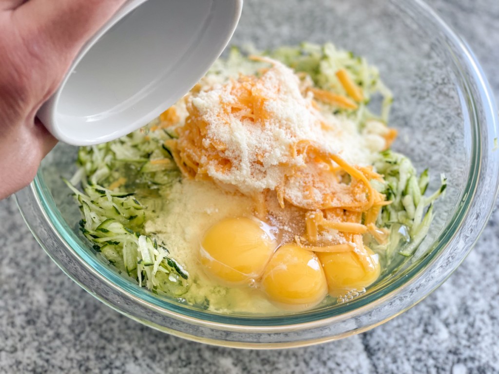 adding eggs to shredded zucchini