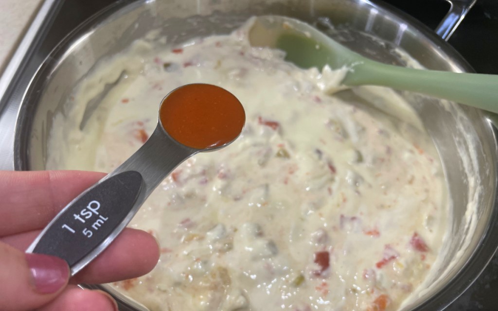adding hot sauce in queso