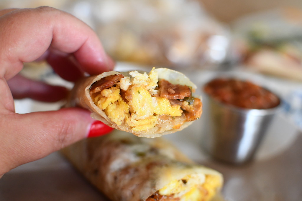 holding keto breakfast burrito with salsa in background