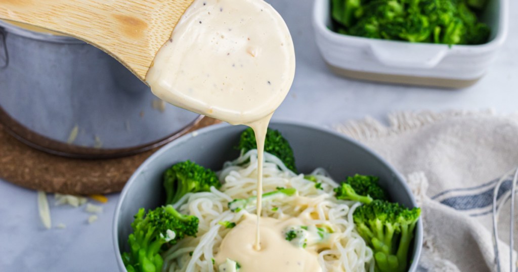 pouring keto cheese sauce on pasta and broccoli