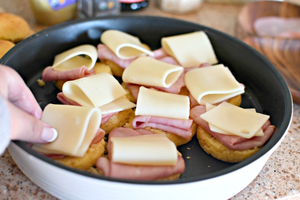 placing cheese on ham and cheese sliders