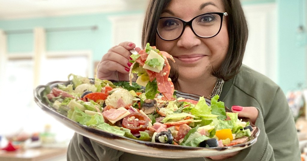 woman holding plate of keto pizza salad