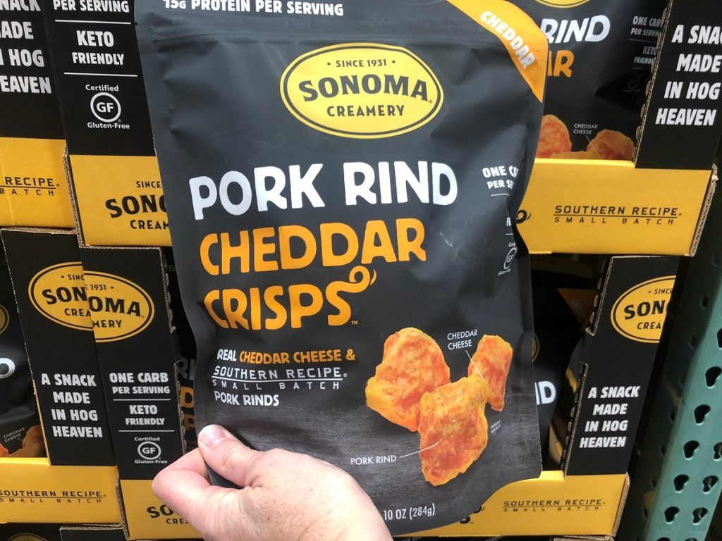 holding bag of pork rind cheddar crisps