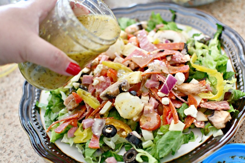 pouring dressing on a keto pizza salad