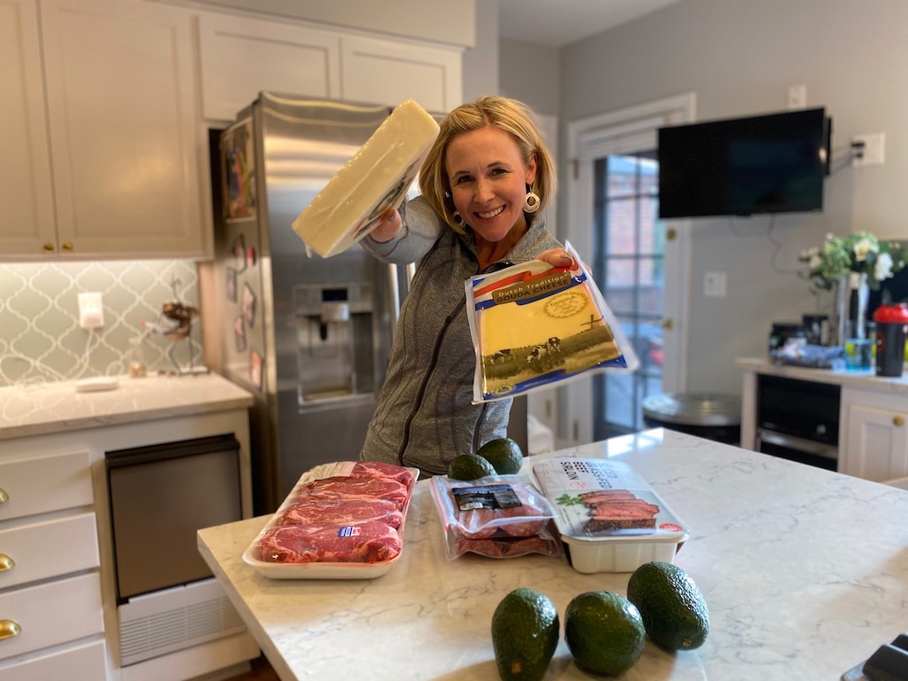 woman holding cheese with steak and avocados on counter