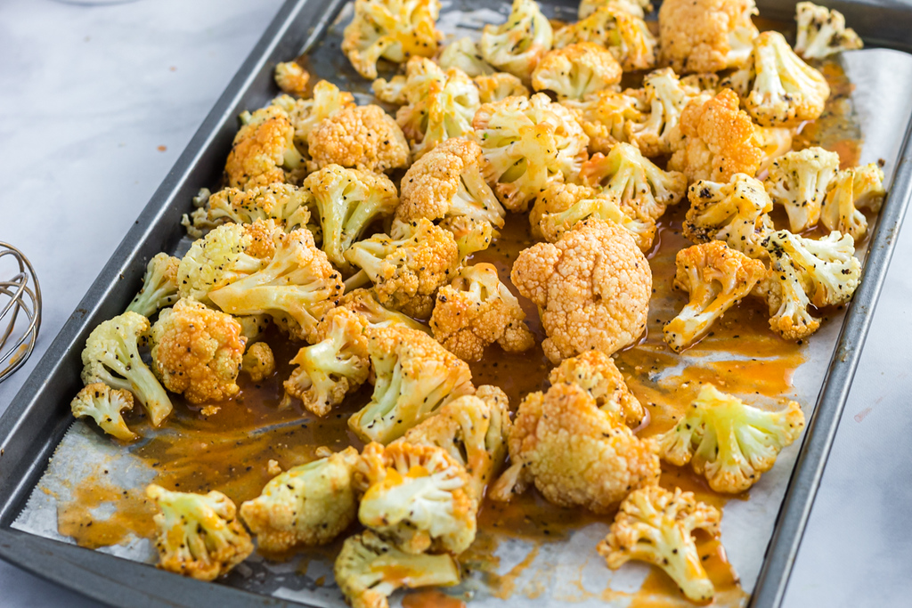 buffalo cauliflower bites on cookie sheet with parchment paper