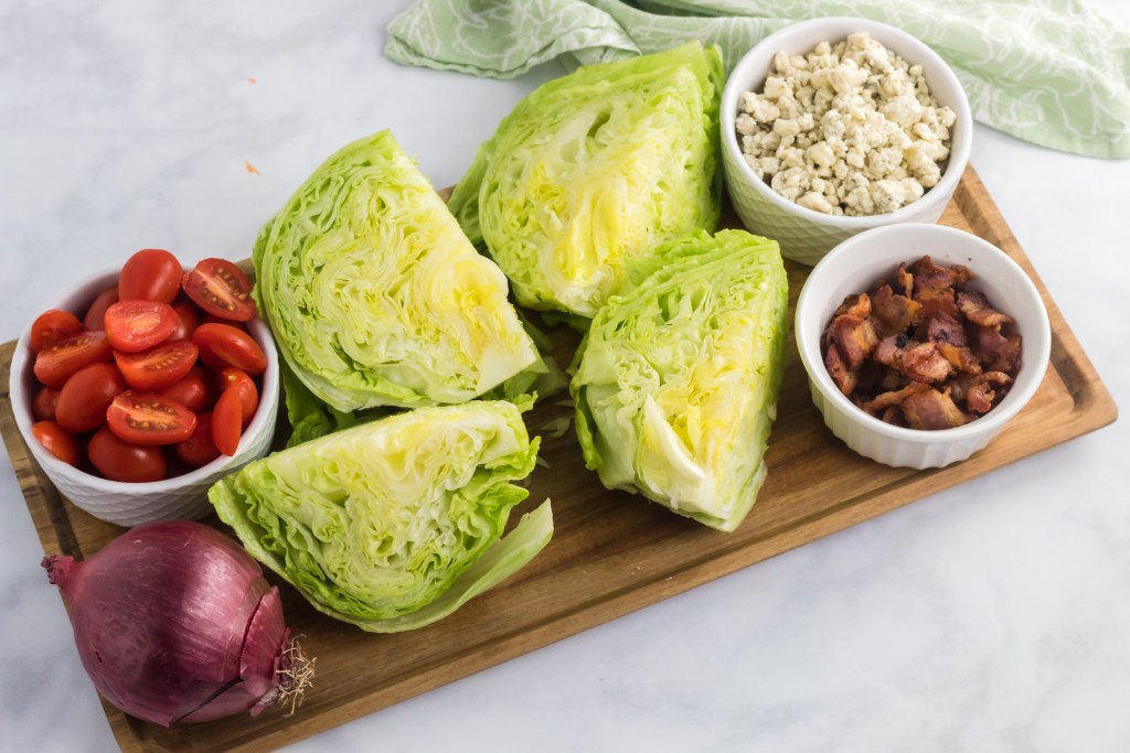 lettuce, tomatoes, onion, and toppings on cutting board