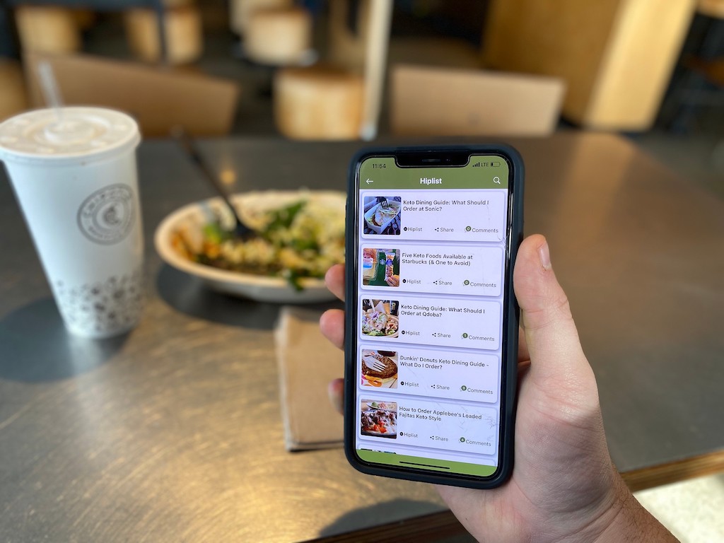 holding smartphone at a restaurant with Hip2Keto app on the screen