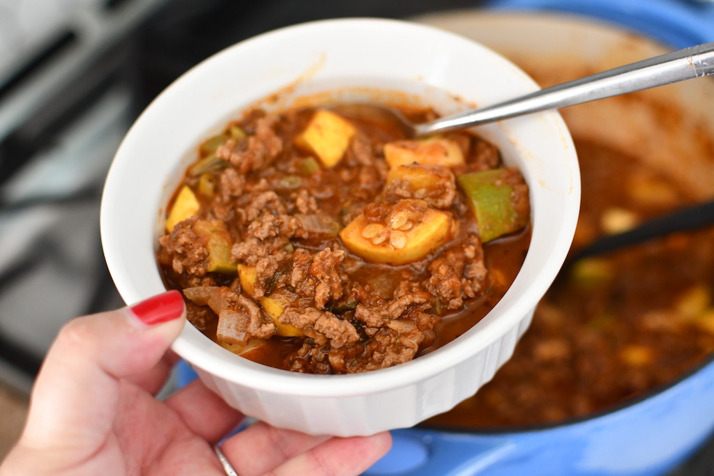 holding white bowl of keto beef goulash 