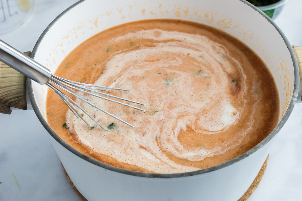 stirring keto tomato basil soup in pot 