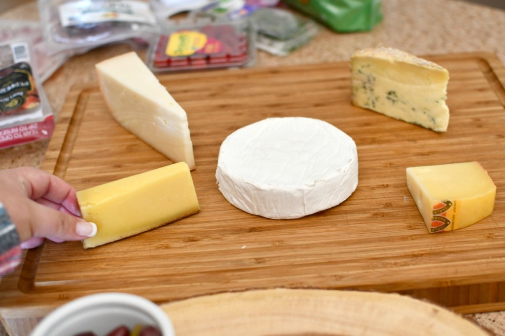 placing a variety of cheeses on a board