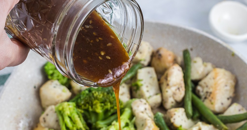 pouring keto teriyaki sauce over stir fry