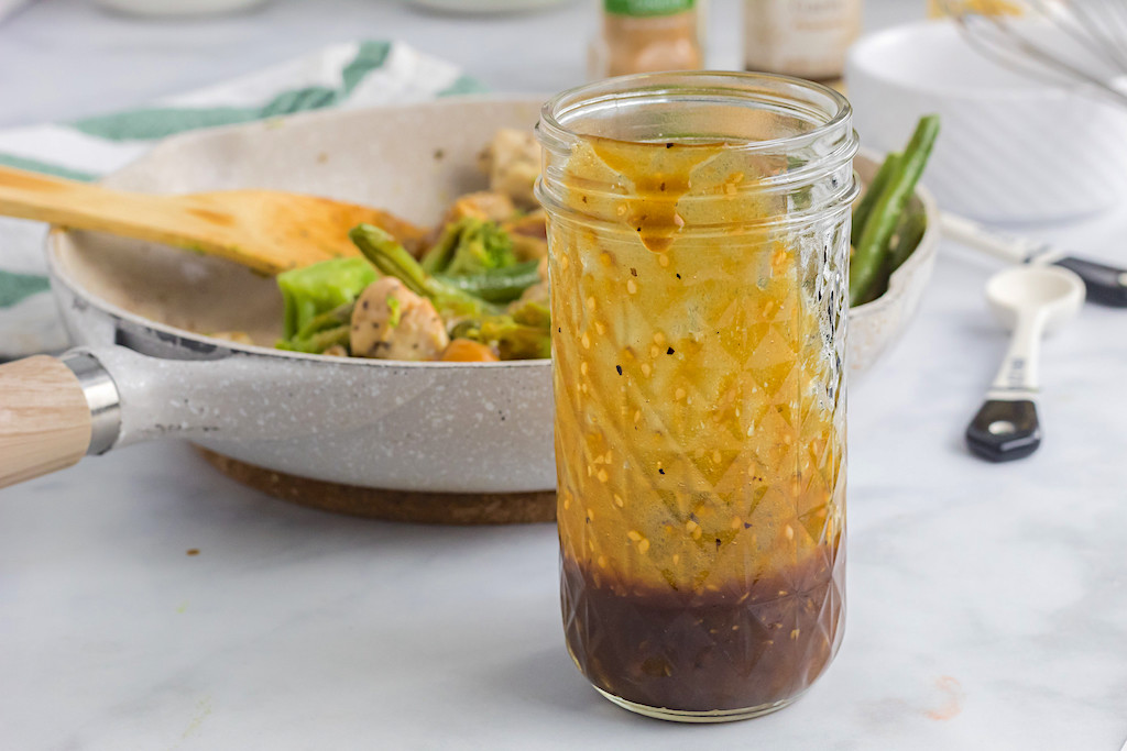 keto teriyaki sauce in jar with pan with veggies in the background