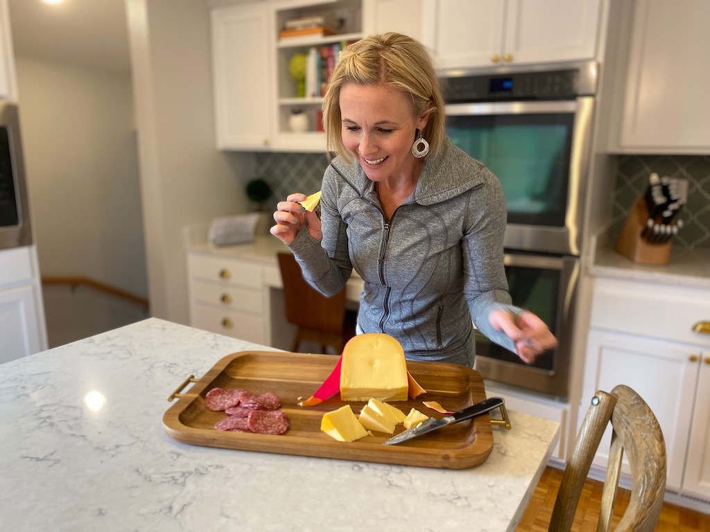 woman eating meat and cheese on a cutting board