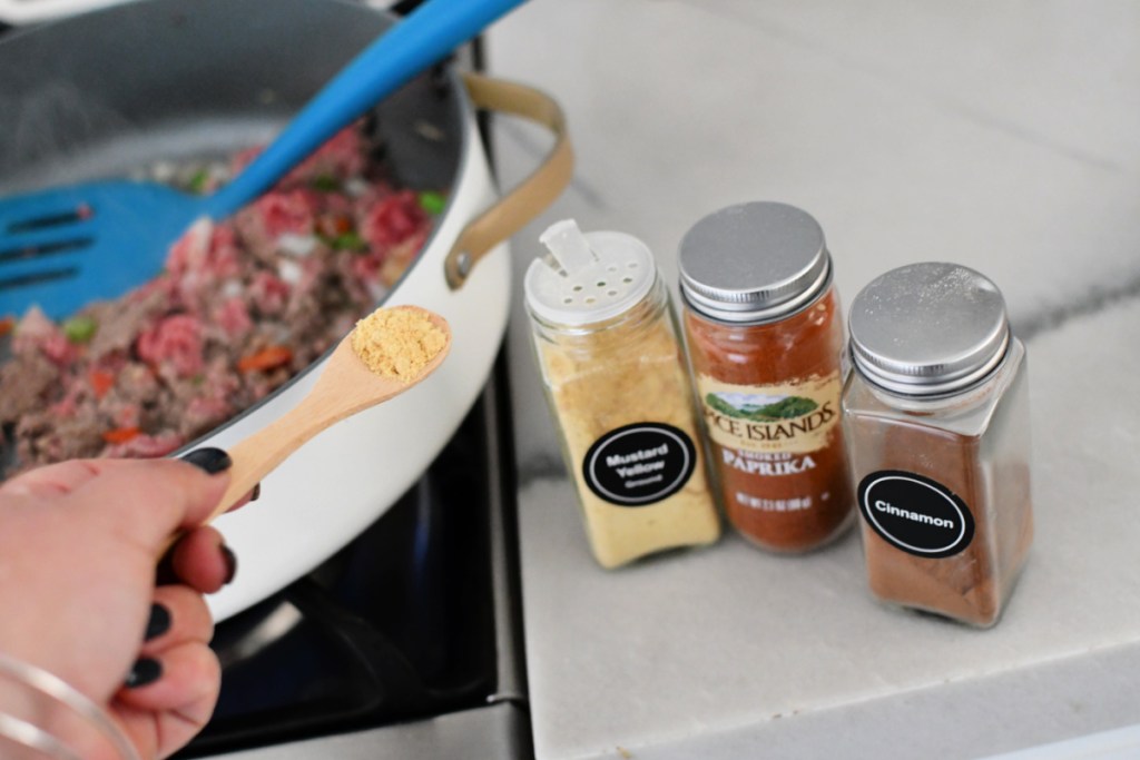 Adding spices to a skillet of keto sloppy joes.