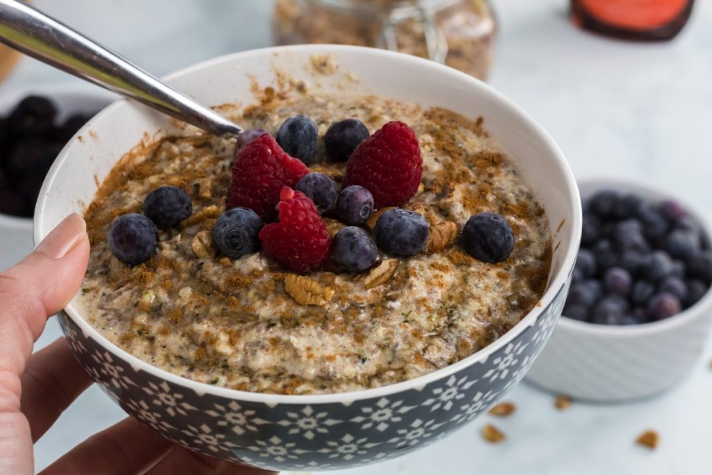 holding bowl of keto oatmeal with berries 