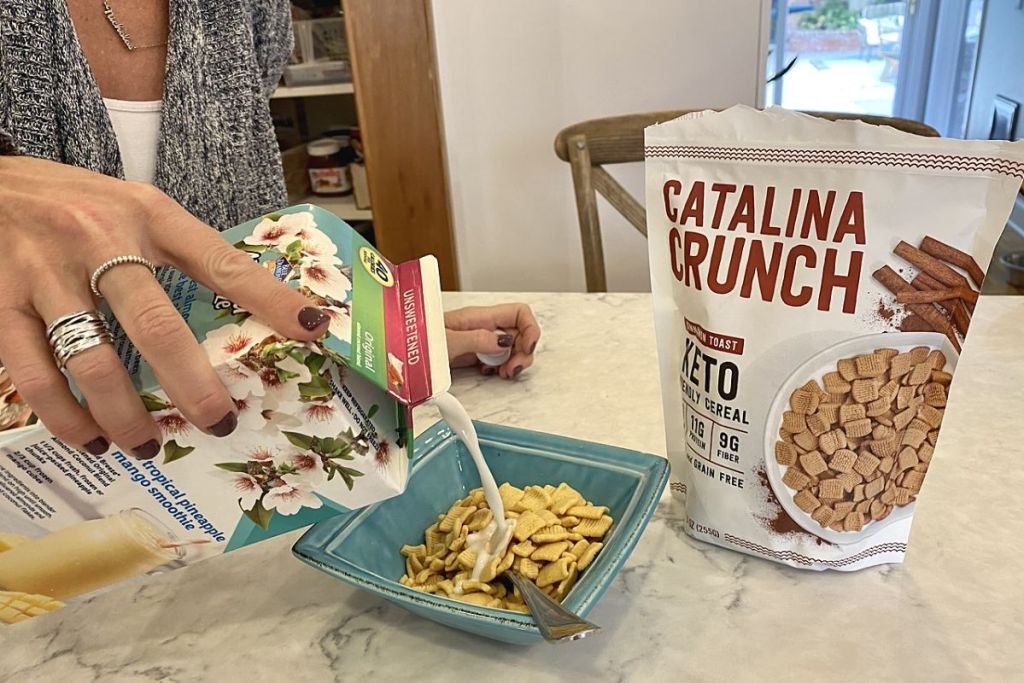 A woman pouring milk into a bowl of cereal in a kitchen