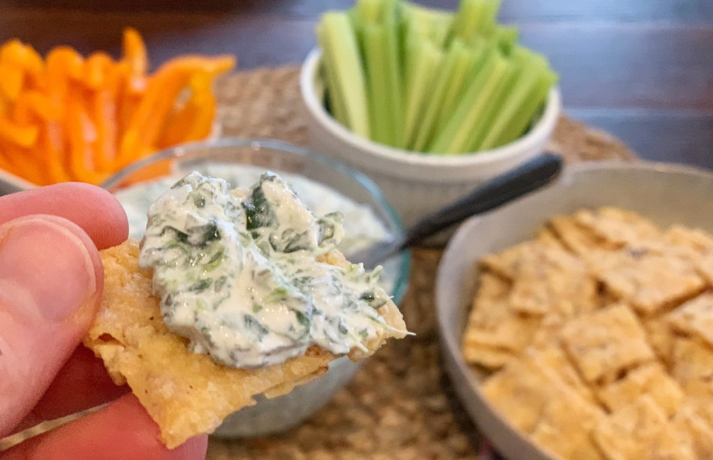 hand holding low carb cracker with dip