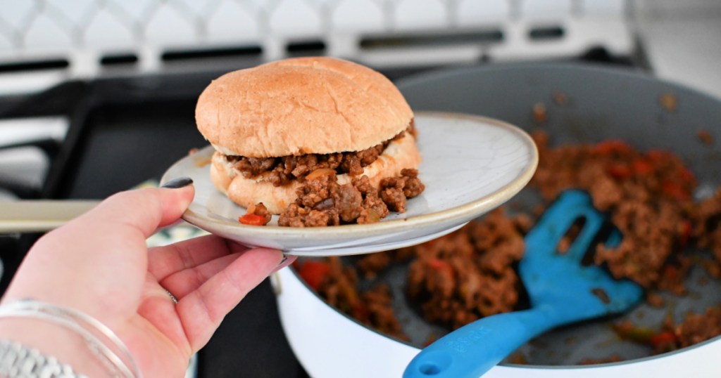 Holding a plate with keto sloppy joe sandwich nest to skillet.