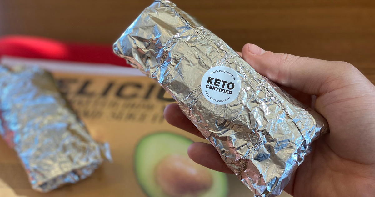 hand holding wrapped taco with keto certified sticker on it 