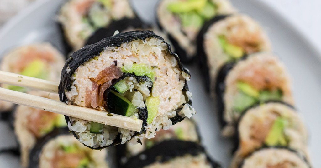 chopsticks holding keto sushi roll piece