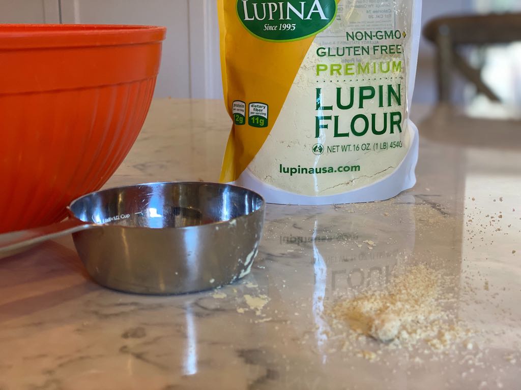 lupin flour with measuring cup by mixing bowl