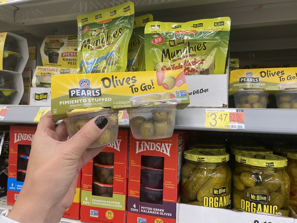 holding snack packs of olives at Walmart