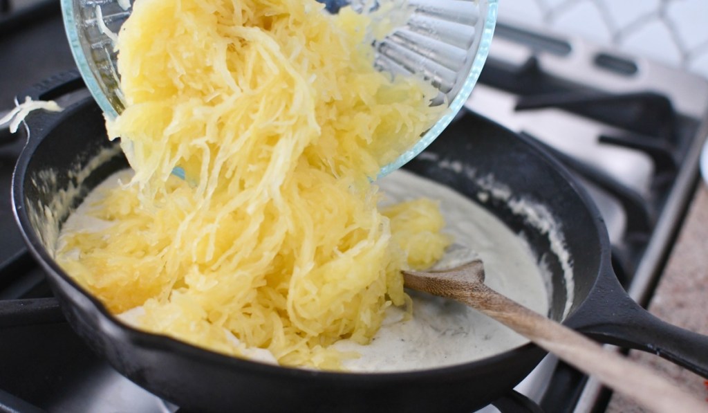 pouring spaghetti squash into alfredo sauce