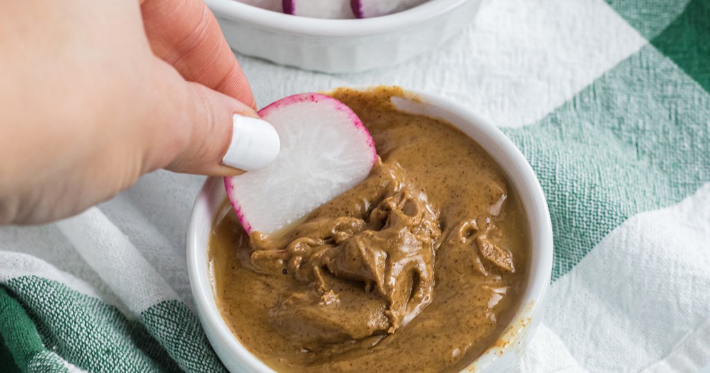 dipping radish slice in peanut butter