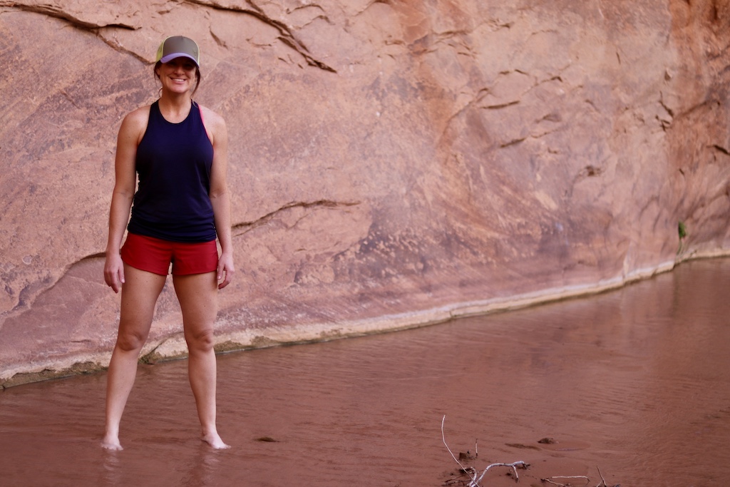 woman wearing tank top, shorts, and hat outside by a canyon