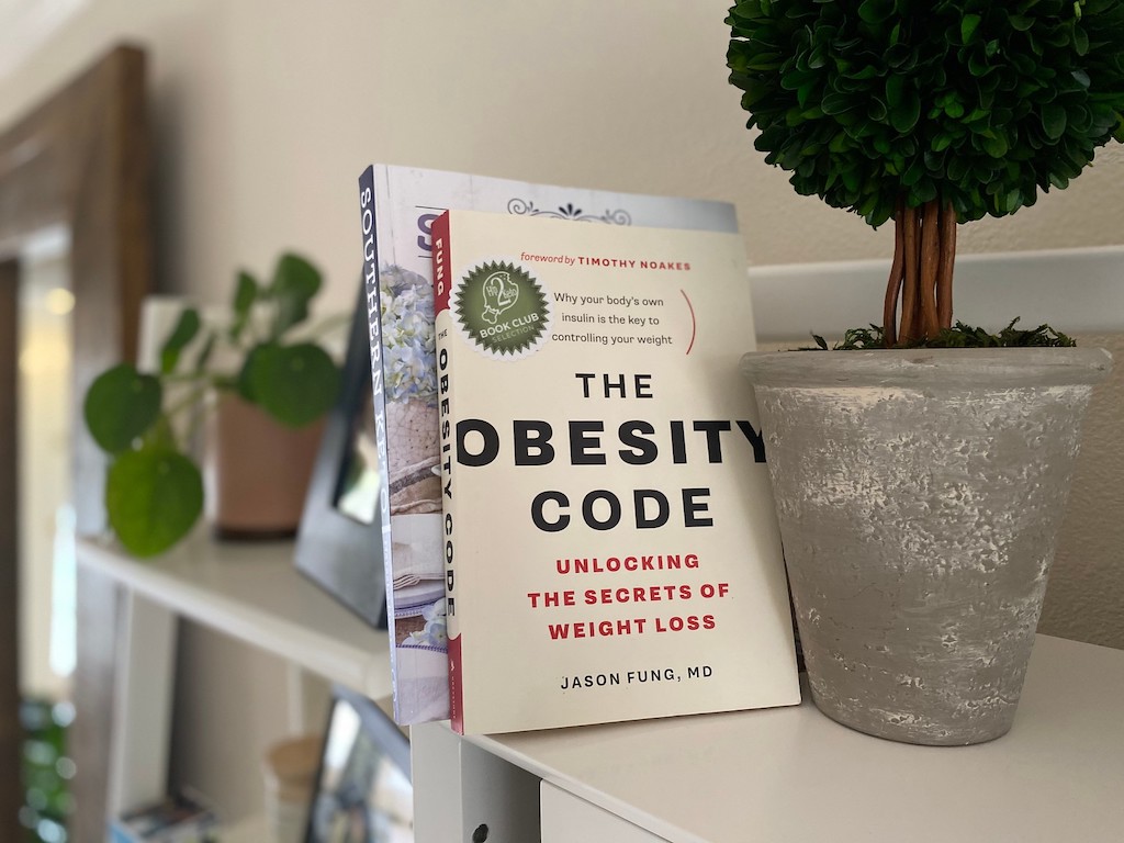 The Obesity Code book sitting on shelf with plants 