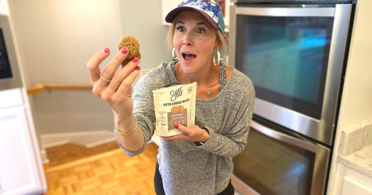 A woman standing in a kitchen holding some superfat keto cookies