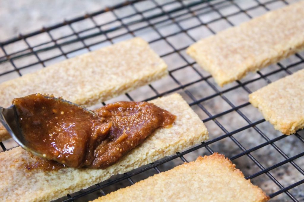 spreading caramel filling on shortbread cookie