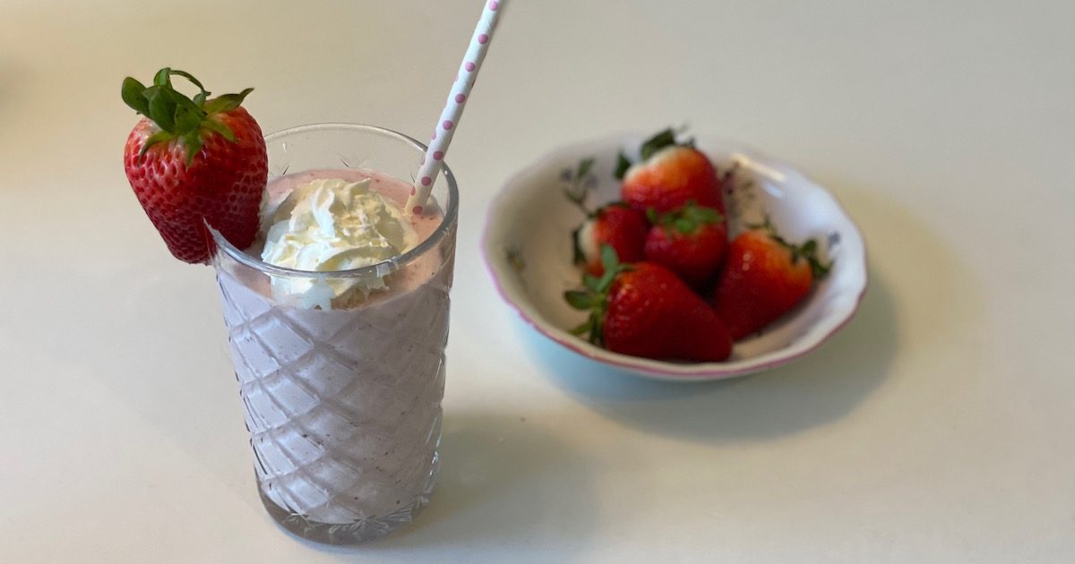 strawberry milkshake next to bowl of strawberries