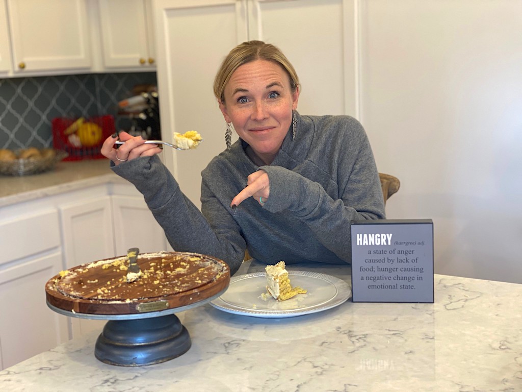 woman eating next to hangry sign