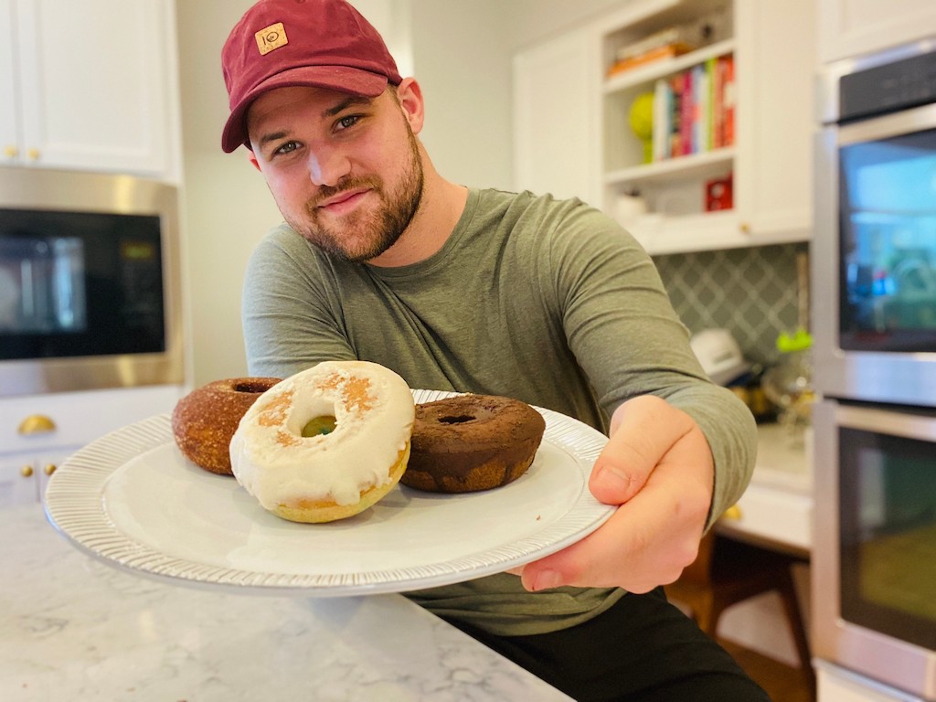 man holding a plate of white and chocolate donuts