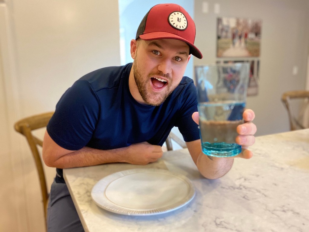 uomo con un bicchiere d'acqua blu