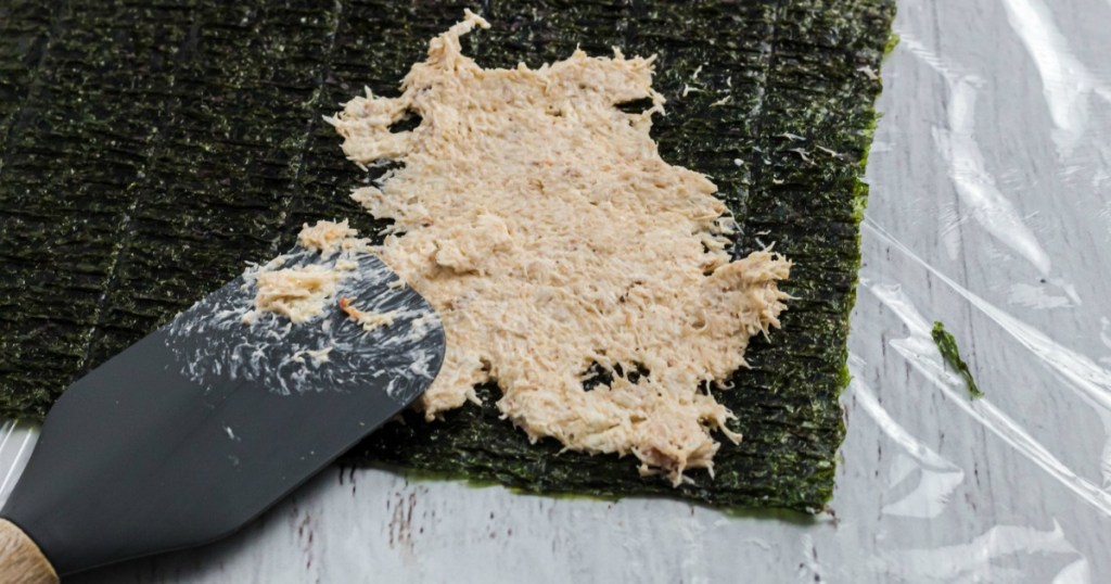 spreading crab meat on sushi nori with spatula 