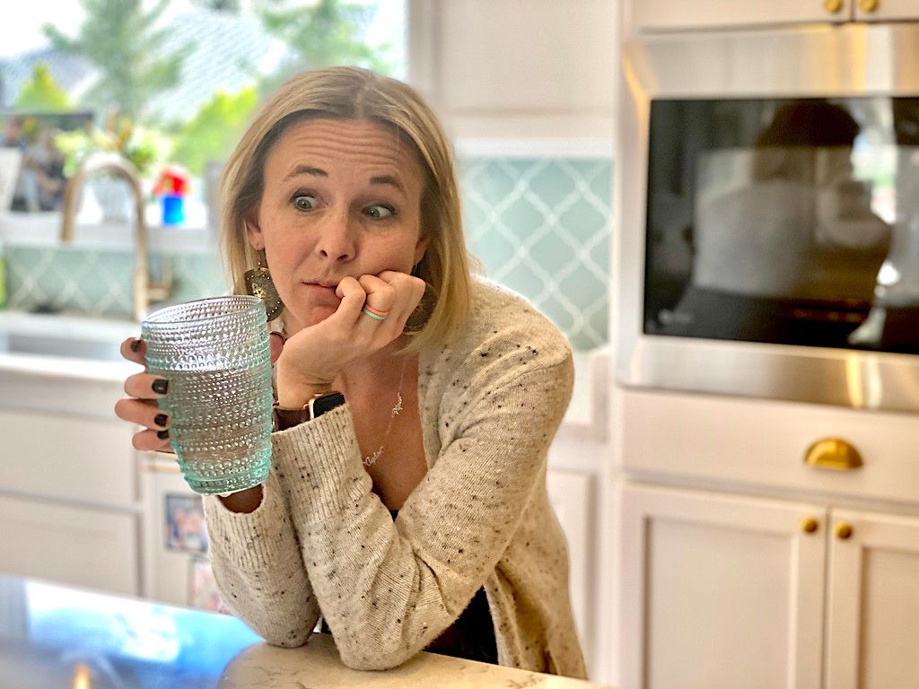 woman looking at cup of water confused