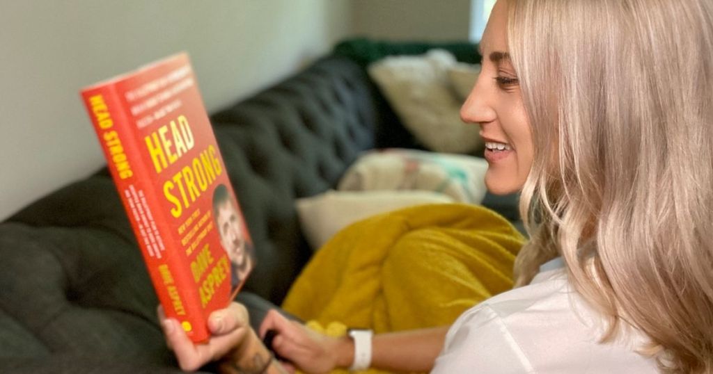 Woman sitting on a couch looking at Head Strong hardcover book