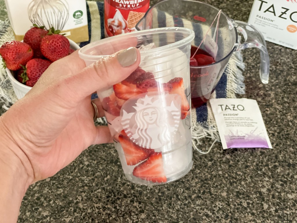 holding a glass with ice and strawberries