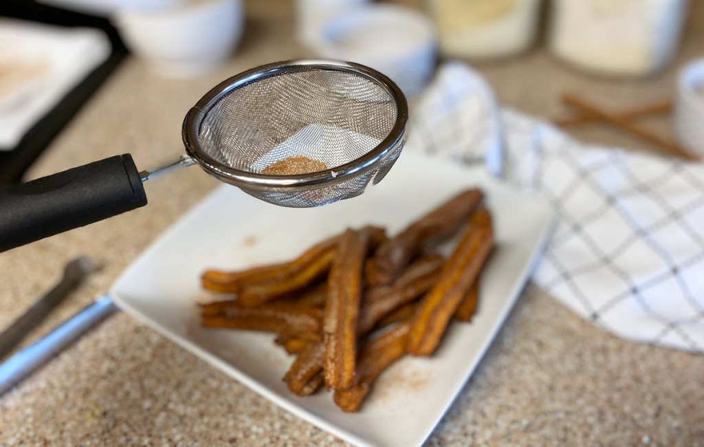 dusting churros with cinnamon sweetener blend