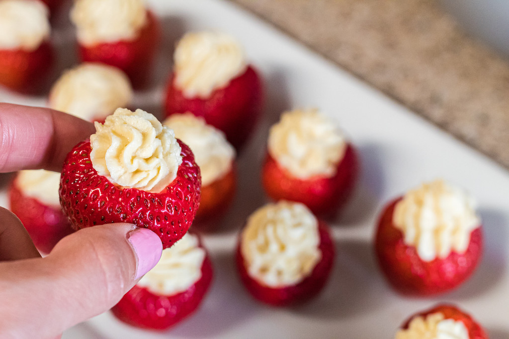 holding cheesecake stuffed strawberry