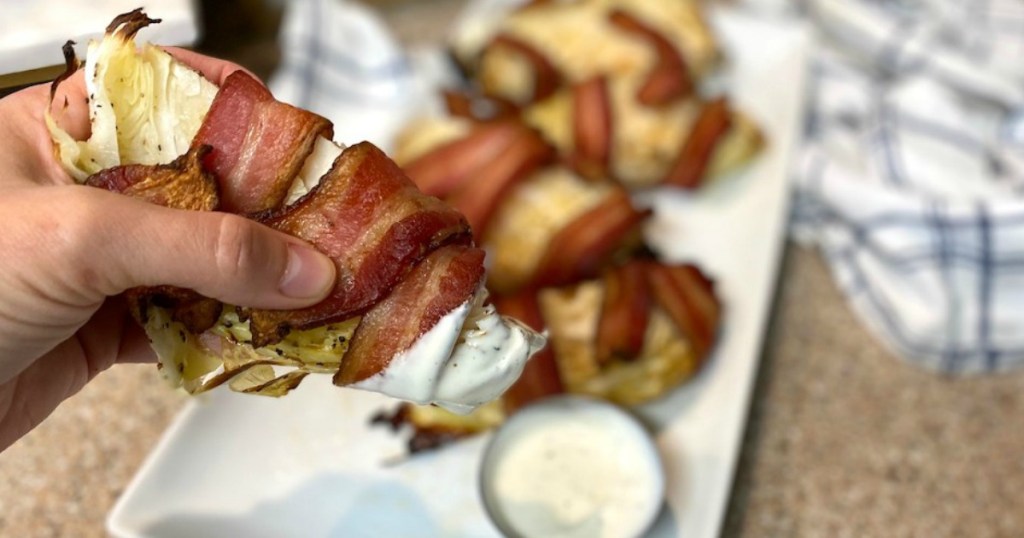 holding bacon-wrapped cabbage wedge that's been dipped in ranch