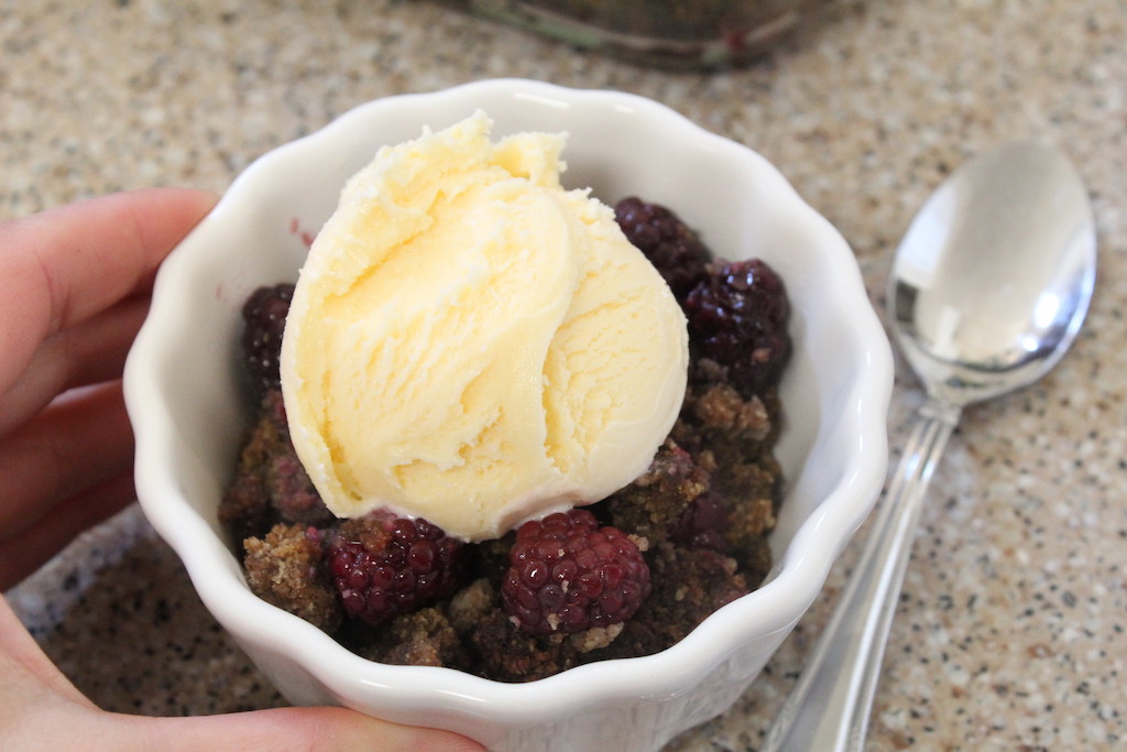holding berry cobbler with scoop of ice cream on top 