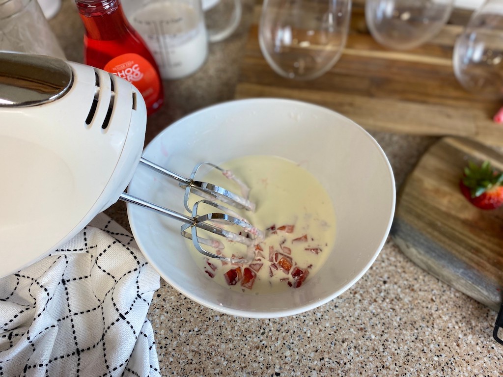 using mixer in bowl with cream and strawberries