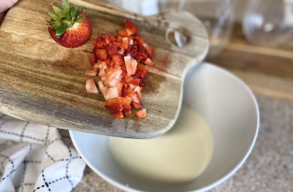 chopped strawberries being added to cream