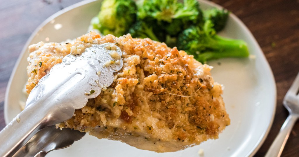 Adding a Parmesan crusted chicken breast to a dinner plate